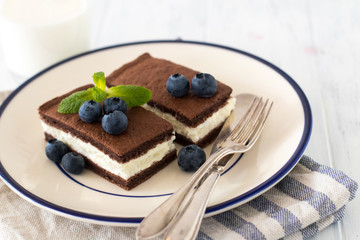 Chocolate biscuit with milk filling and berries on a plate. Chocolate-milk kids dessert.