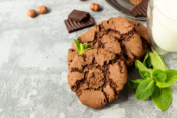 Chocolate cookies for breakfast with mint and hazelnut and a glass of milk on a gray table - 159611108