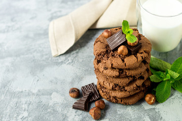 Chocolate cookies for breakfast with mint and hazelnut and a glass of milk on a gray table - 159611112