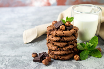 Chocolate cookies for breakfast with mint and hazelnut and a glass of milk on a gray table - 159611129
