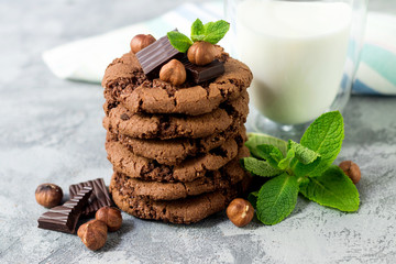 Chocolate cookies for breakfast with mint and hazelnut and a glass of milk on a gray table - 159611142