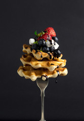 A stack of Belgian waffles with berries.(Strawberry, blueberry), marshmelow, and chocolate sauce on a fork, with levitation - 159611314
