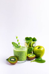 .Green smoothies made of yogurt, spinach, kiwi and apple in glasses on a white background, ingredients around