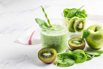 .Green smoothies made of yogurt, spinach, kiwi and apple in glasses on a white background,...