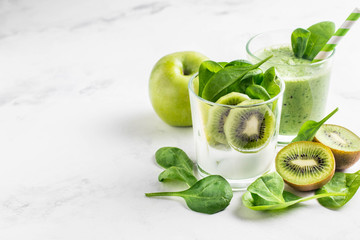.Green smoothies made of yogurt, spinach, kiwi and apple in glasses on a white background, ingredients around - 159611552
