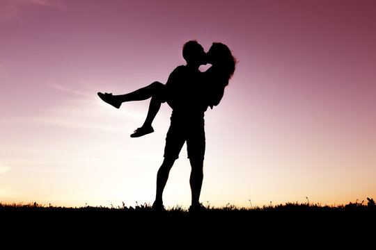 silhouette of romantic lovers with sunset on the back