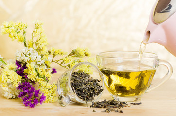 Pouring hot tea from teapot into a cup, healthy drink
