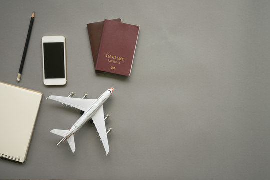 Top view of work desk with blank notebook, Blank name card, smartphone, passport, plane model and glasses on green and yellow background.