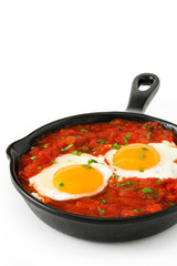 Mexican breakfast: Huevos rancheros in iron frying pan isolated on white background
