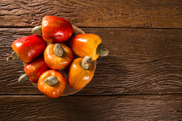 Some cashew fruit over a wooden surface.