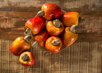Some cashew fruit over a wooden surface.
