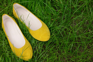 Yellow female shoes on green grass. Blurred macro photo.