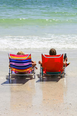 College girls sitting in beach chairs at the waters edge relaxing during summer vacation