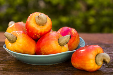 Some cashew fruit over a wooden surface.