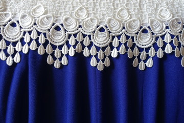 Border of white lace over draped blue fabric