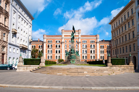 Monument of the Deutschmeister Rossauer Kaserne on a city square among white and orange brick buildings on a warm summer day. Vienna, Austria