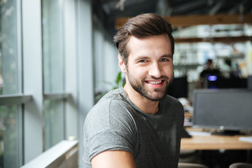 Fototapeta premium Handsome smiling young man sitting in office coworking.