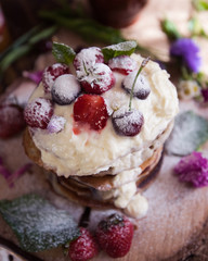 Delicious pancakes with berries and cream on the authentic wooden stand. Summer food still life concept.