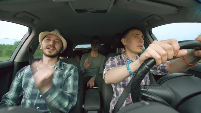 Group Of Happy Friends In Car Singing And Dancing While Drive Road Trip