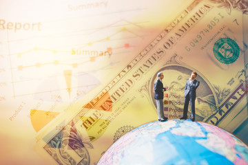 Miniature people on the globe world map with  graph and dollars banknotes  for finance and business concept