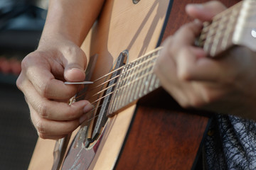 Closeup hand with pick play on acoustic guitar.