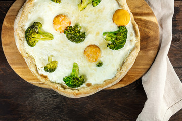 Egg and broccoli pizza, shot from above on rustic texture