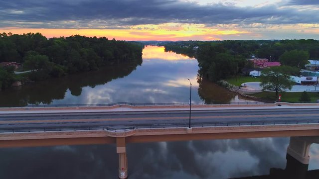 Flying over scenic bridge, smooth waters reflecting moody twilight sky.
