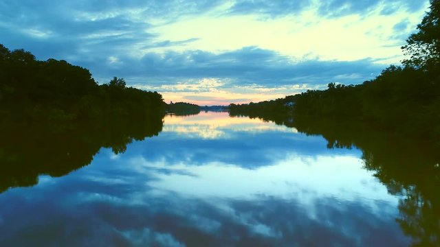 Flying low over smooth water&rsquo;s surface reflecting deep blue twilight sky.
