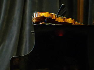 Violin on the grand piano in a concert hall