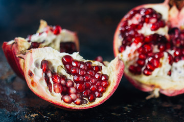 Quarter of pomegranate fruit on black rustic surface.