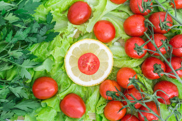 Cherry tomatoes covered with water drops lie on the basis of green lettuce leaves