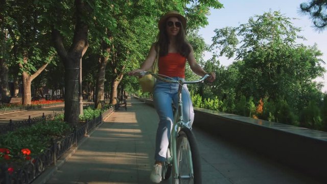 young beautiful woman riding a bicycle in a park