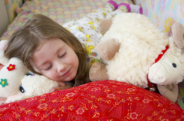 girl sleeping in bed with toys