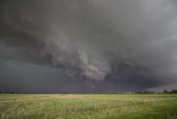 A rotating wall cloud hangs ominously under the base of a tornado-warned supercell thunderstorm.