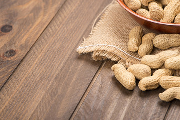 From above plate with whole peanuts on canvas bag. Wooden background. Copy space.