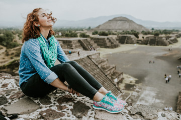 .Young carefree female tourist enjoying the pyramids of Teotihuacan in Mexico. Lifestyle portrait.