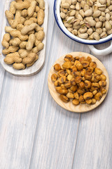 From above  pistachios and toasted corn on wooden background. Vertical studio shot.