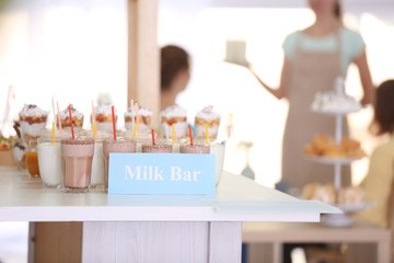 Different drinks and desserts with visitors sitting in milk bar