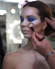 Make-up artist makes art make-up paint at the models eye making shadows