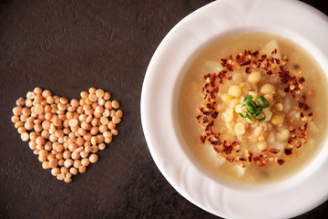 Split pea soup is decorated with red pepper flakes on black stone slate background.