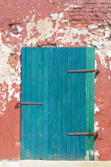 vintage old wooden green barn door in brick wall with cracked plaster and paint