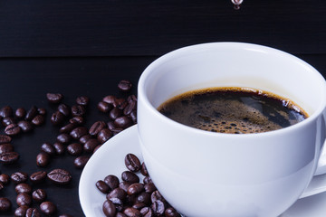 Hot coffee in the white cup and roasted on dark background
