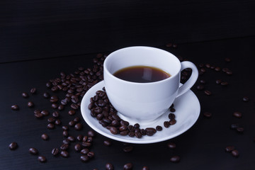 Hot coffee in the white cup and roasted on dark background
