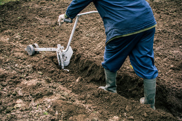 A man holding a metal plow. He was a plow plowing the land.
