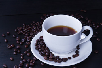 Hot coffee in the white cup and roasted on dark background
