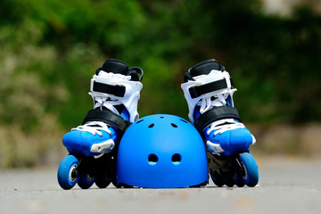 Roller inline skates with helmet in skate park on gray asphalt background
