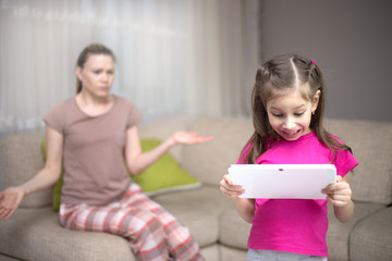 Mother frustrating that her daughter playing video games.
