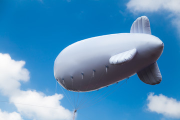 Inflatable dirigible on the background of the sky with a place for the logo