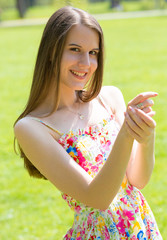 Portrait of young beautiful woman with long hair wearing flower dress in green spring park