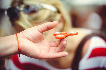 The spinner in the hand rotates, against the background of people, keeps on one finger